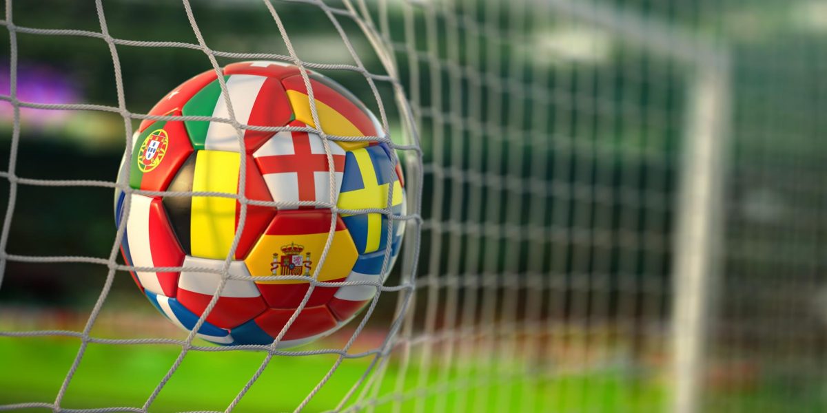 Photo via https://img.goodfon.com/original/8400x4200/3/27/football-ball-with-flags-of-european-countries-in-the-net-of.jpg under the Creative Commons License
